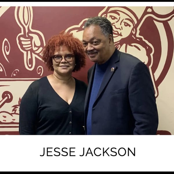 Jesse Jackson and a woman smiling in front of a Kountry Kitchen mural.