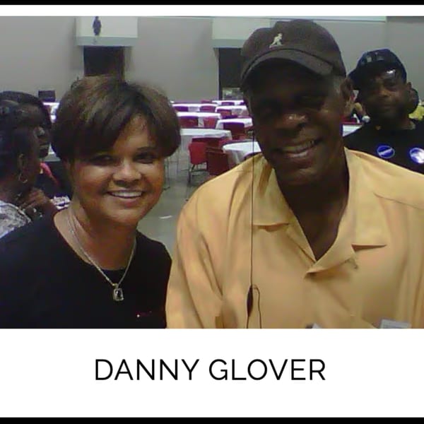 Danny Glover smiling with a woman at Kountry Kitchen, with dining tables in the background.