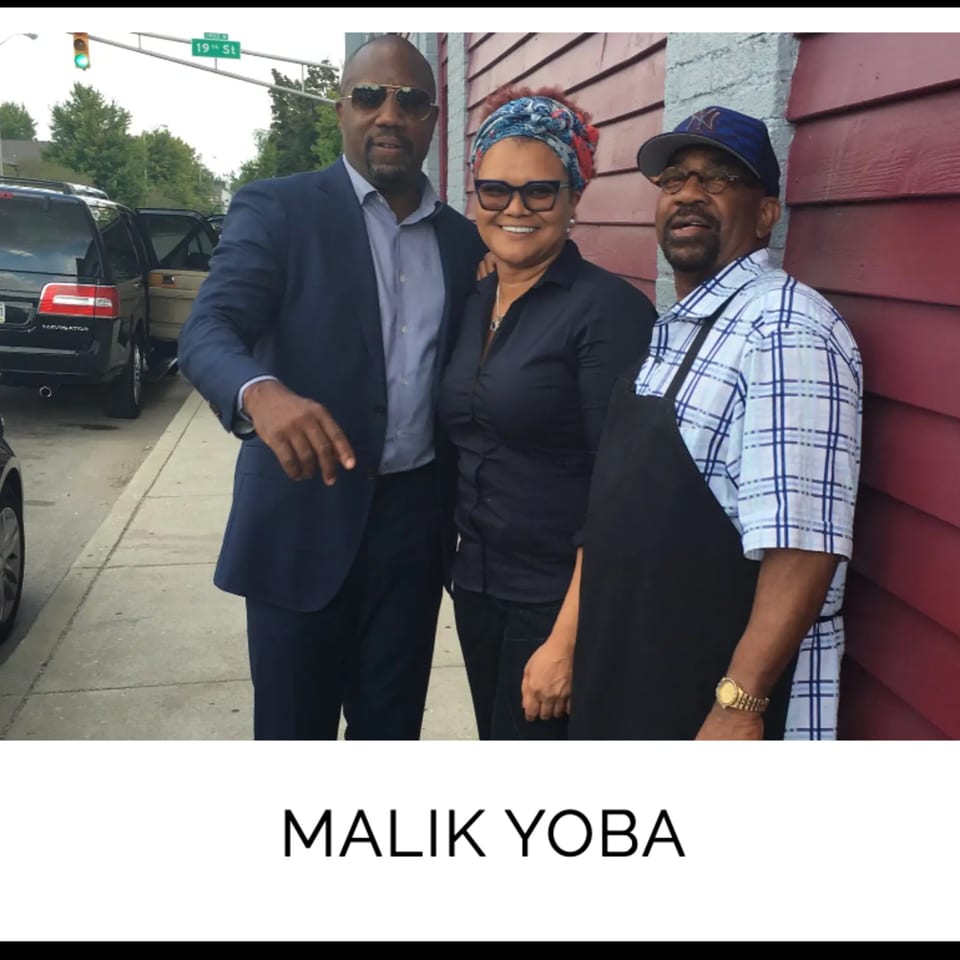 Actor Malik Yoba, a woman, and a man in an apron pose outside Kountry Kitchen soul food restaurant.