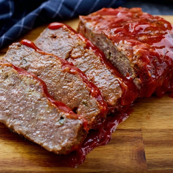 Slices of Kountry Kitchen's soul-food meatloaf, topped with a rich red glaze, on a wooden board.