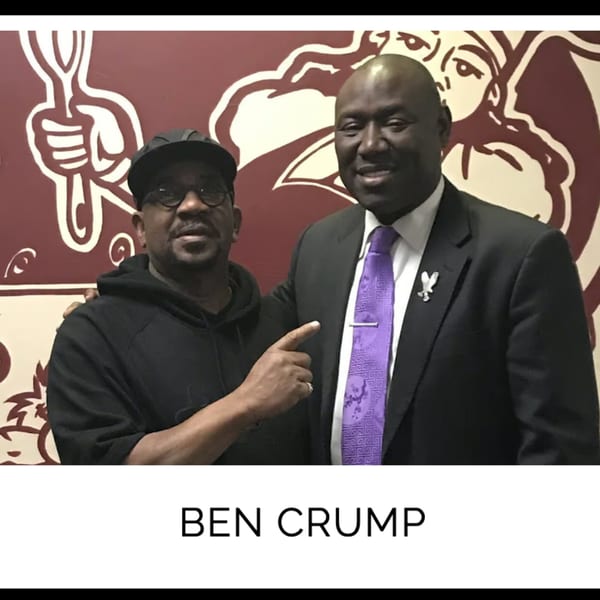 Ben Crump and another man smiling in front of a Kountry Kitchen wall mural.
