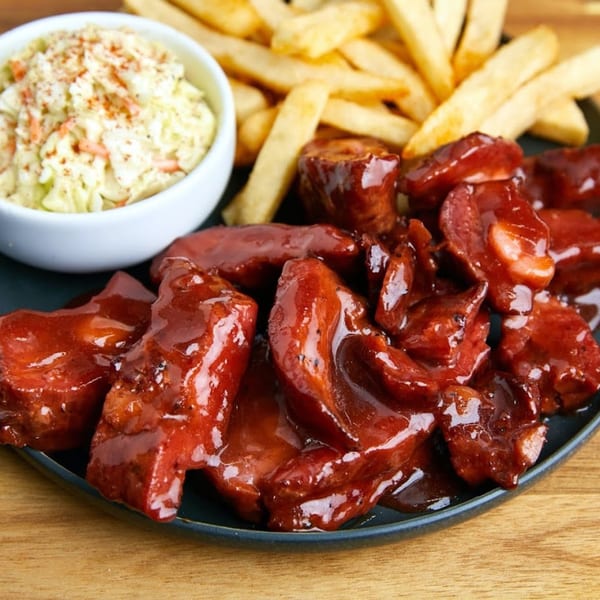 Kountry Kitchen's BBQ ribs, golden fries, and creamy coleslaw on a dark plate.