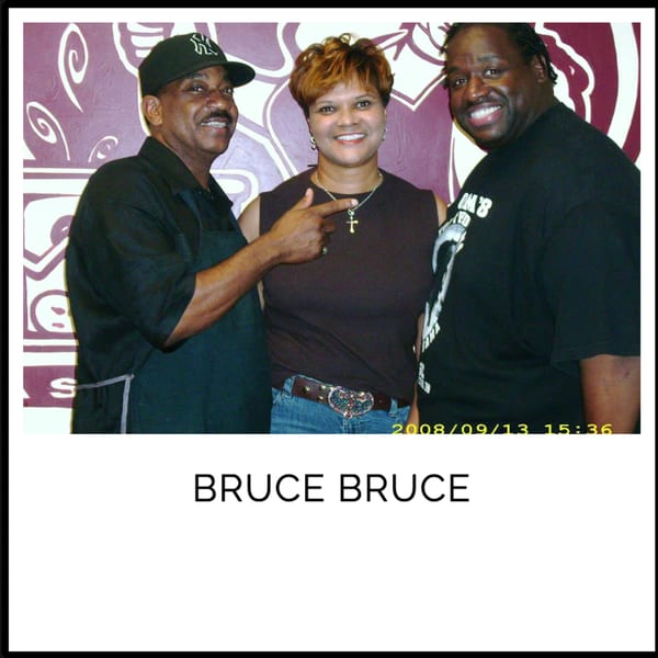 Three smiling people, two men and one woman, posing together in front of a purple and white patterned wall.