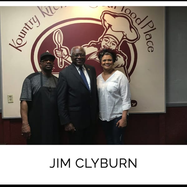 Jim Clyburn with two Kountry Kitchen staff members in front of the restaurant's logo.