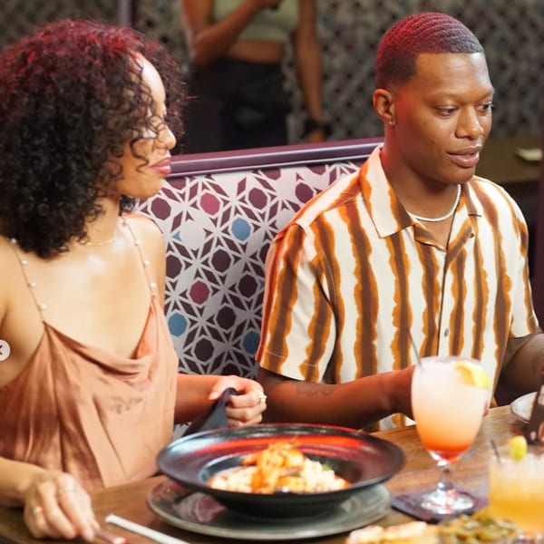 A couple enjoying a meal and drinks at Kountry Kitchen, with a plate of soul food in the foreground.