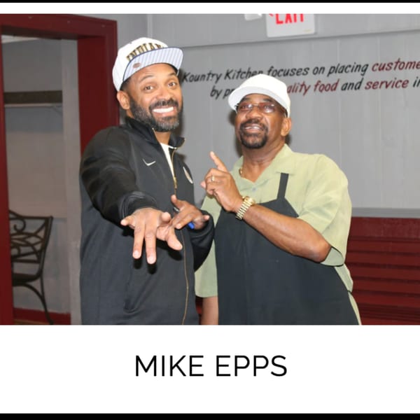 Comedian Mike Epps and a Kountry Kitchen staff member smiling and gesturing in the restaurant.