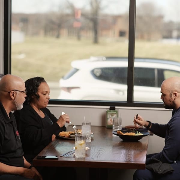 Three patrons enjoying soul food at a table by a large window at Kountry Kitchen.