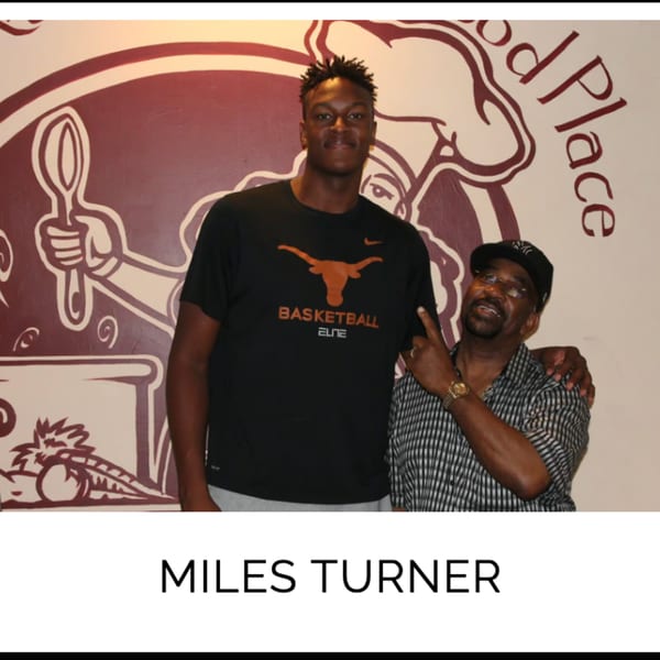 Miles Turner and another man posing in front of a Kountry Kitchen wall mural.