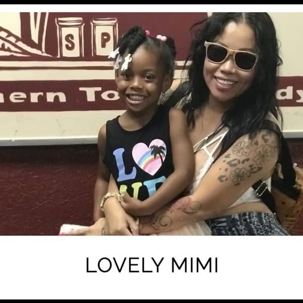 A woman in sunglasses holds a smiling young girl in front of a Kountry Kitchen sign.
